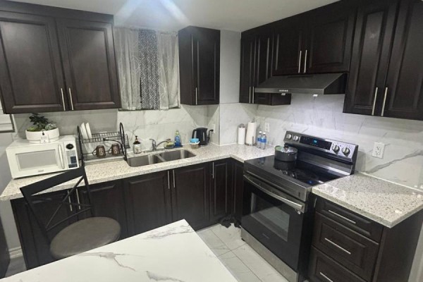 Kitchen featuring dark cabinets, stainless steel appliances, and marble countertops. - 1 Grape Trail, Brampton