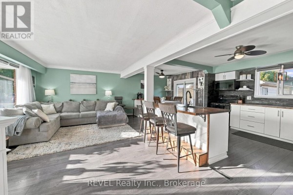 Living room with a large grey sectional sofa and a kitchen island with bar stools. - 1 Idylwood Road, Welland