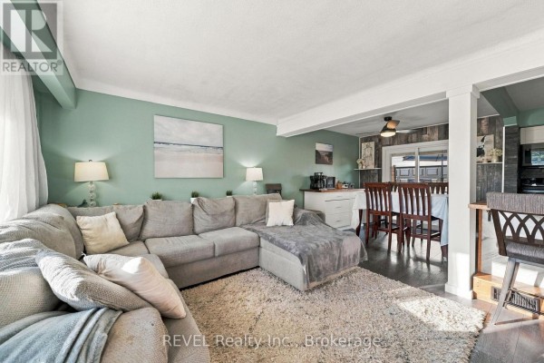 Kitchen island with bar stools facing a dining area with a table and chairs. - 1 Idylwood Road, Welland