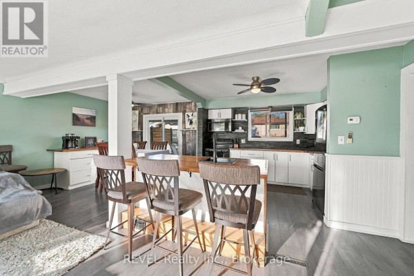 Living room with a fireplace, large window with view of the street, and a grey sectional sofa. - 1 Idylwood Road, Welland