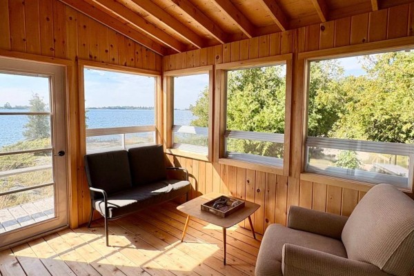 Sunroom with water view, sofa, armchair, coffee table, wood paneling - 1 Island 352c Carling