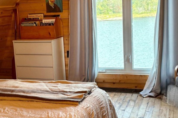 Bedroom with waterfront view, wood paneling, large window, and bed - 1 Island 352c Carling