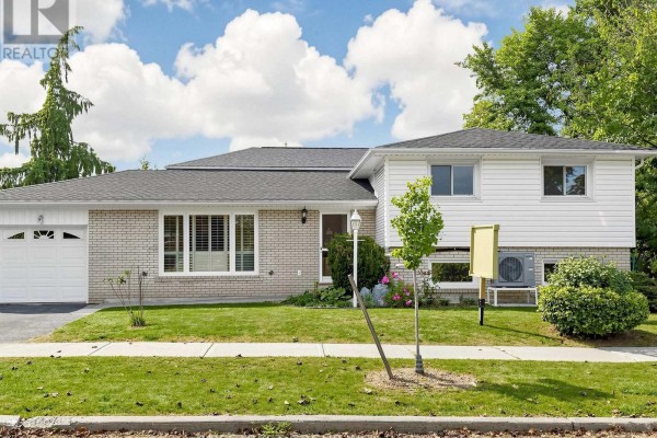 Front view of a white and light brick house with a garage and manicured lawn. - 1 Lesgay Crescent, Toronto