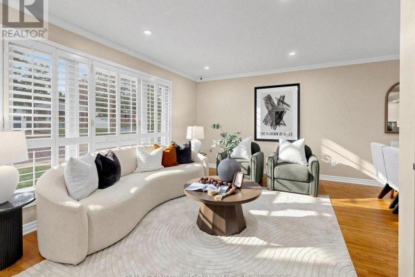 Living room featuring a curved sofa, two green armchairs, coffee table, and wooden floor. - 1 Lesgay Crescent, Toronto