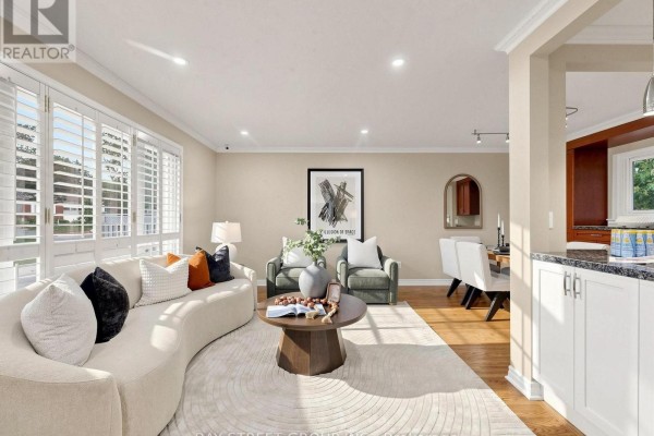 Living room and dining area with a sofa, dining table, and white kitchen cabinets visible. - 1 Lesgay Crescent, Toronto