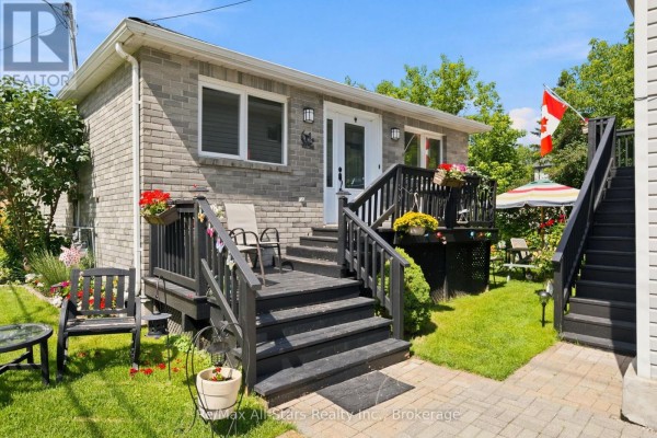 Side view of a grey brick bungalow with a detached double garage and paved driveway. - 1 Maple Grove Street, Whitchurch Stouffville