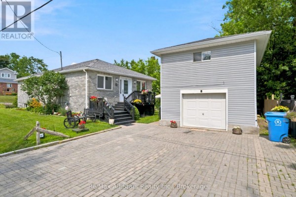Front exterior showing the grey brick bungalow, detached garage, and paved driveway. - 1 Maple Grove Street, Whitchurch Stouffville