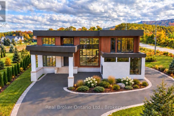 Front view of modern concrete and wood home with manicured landscaping and paved driveway. - 1 Meadowlark Way, Clearview