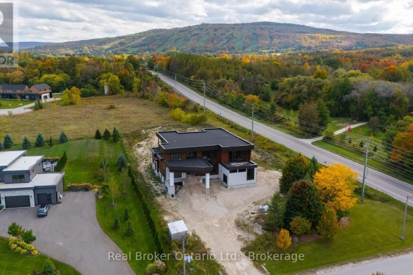 Aerial view of a modern home on a hill overlooking a road and colorful autumn trees. - 1 Meadowlark Way, Clearview