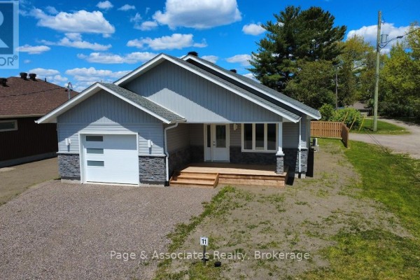 Front exterior of a grey house with white garage door, stone accents, and wooden porch. - 1 Moon Court, West Nipissing
