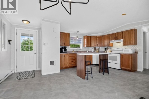 Kitchen with wood cabinets, white countertops, and a center island with stools. - 1 Peridot, Moncton