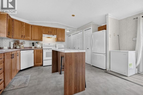 Kitchen showing wood cabinets, white appliances, and a large freezer and refrigerator. - 1 Peridot, Moncton