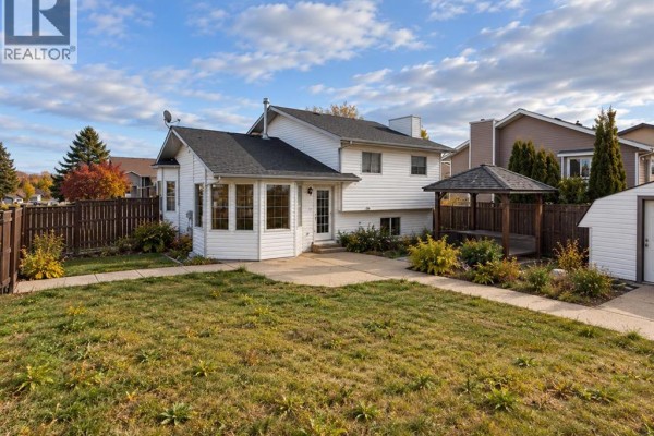 Backyard view showing a white house with a sunroom, wooden gazebo, and fence. - 1 Pickering Close, Sylvan Lake