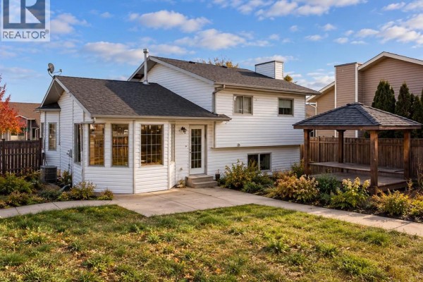Rear view of the house featuring a sunroom, backyard, and wooden gazebo. - 1 Pickering Close, Sylvan Lake