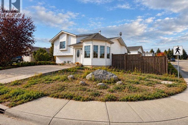 Street view of the house from a corner lot, featuring a large rock in the front yard. - 1 Pickering Close, Sylvan Lake