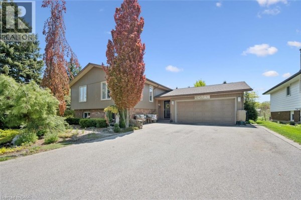 Side view of the house entrance with a large driveway and mature trees. - 1 Pintail Drive, Elmira