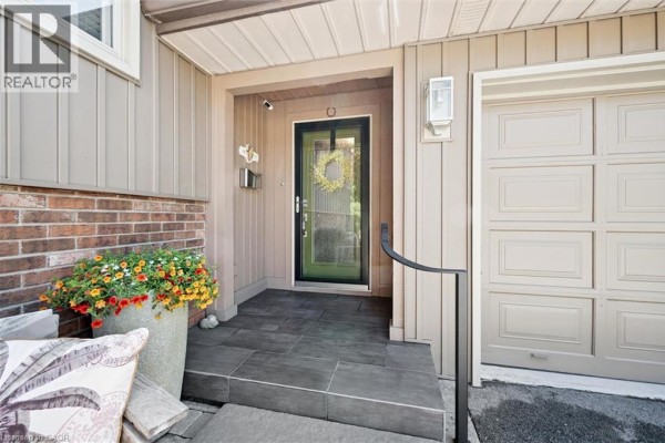 Close-up of the front entrance with a glass door, porch, and garage. - 1 Pintail Drive, Elmira
