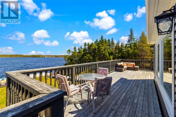 Wooden deck with patio furniture and a table, overlooking a lake and trees. - 1 Ryan's Lane, Brigus Junction