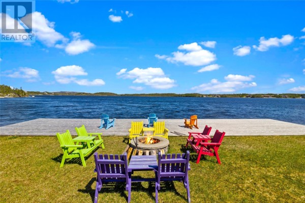 Outdoor seating area with a fire pit and colorful chairs arranged on a grassy lawn. - 1 Ryan's Lane, Brigus Junction