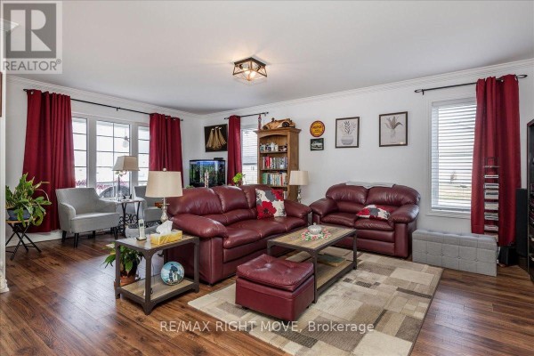 Living room with dark red leather sofas, wood flooring, and a geometric area rug. - 1 Sinclair Crescent, Ramara