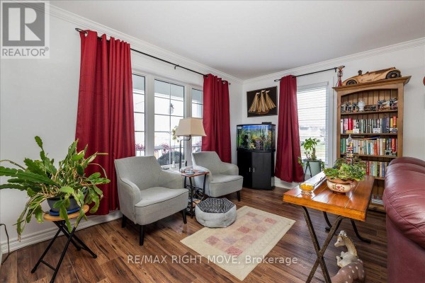 Living room seating area with two grey armchairs, a small table, and plants. - 1 Sinclair Crescent, Ramara
