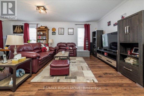 Spacious living room with sofas, television, entertainment unit, and floor-to-ceiling windows. - 1 Sinclair Crescent, Ramara