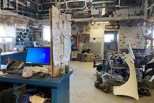 Interior view of a parts office with a computer, desk, and walls covered in automotive parts and paperwork. - 1 Tindall Land, Brokenshell Rm No  68