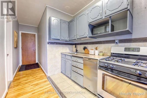 Narrow kitchen view featuring gray cabinets, gas stove, and tiled backsplash - #1 Upper - 1548 St. Clair Parkway, St  Clair