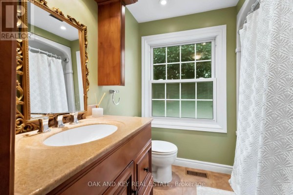 Bathroom vanity, mirror, toilet, and shower curtain - 1 Vanier Place St Thomas