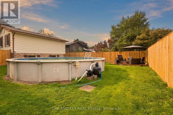 Backyard with above-ground pool, deck, patio furniture, and fence - 1 Vanier Place St Thomas