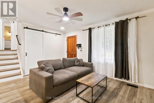 Open concept living area with sofa, kitchen island with stools, and stairs. - 1 Vanier Place, St  Thomas