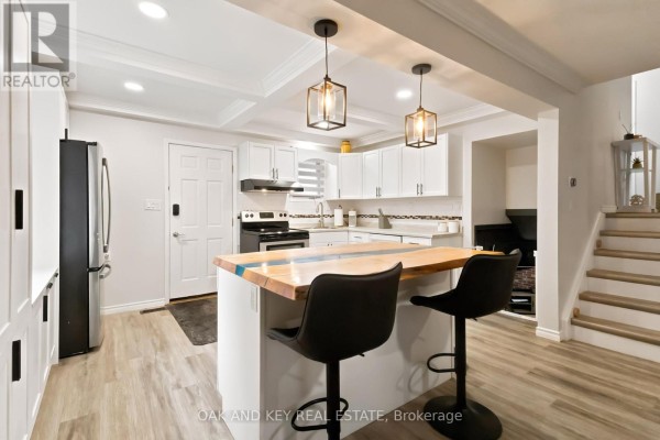 Modern kitchen with wood & resin island, pendant lights, and staircase - 1 Vanier Place St Thomas