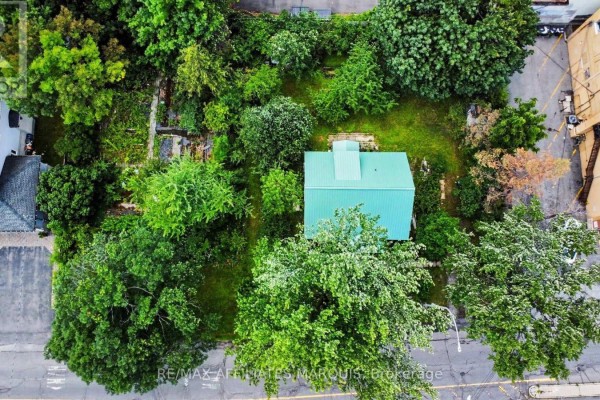 Overhead aerial view of a small house with a green metal roof nestled within a dense green forest. - 1 Withrow Avenue, Ottawa