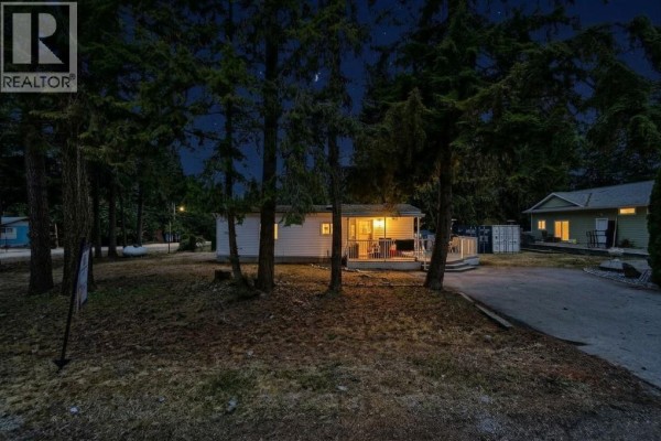 Front view of a mobile home with a black fence and parking area. - 1 Wolfe Street, Sicamous