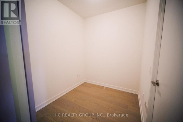 Empty room with white walls, light wood floors, and a closed door on the right. - 4512 - 1 Yorkville Avenue, Toronto