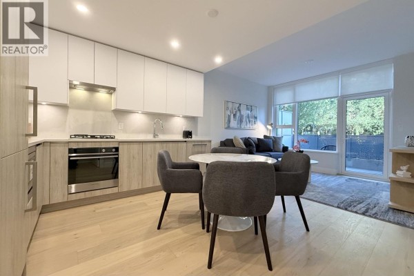 Apartment dining area with a marble table and four chairs next to a compact kitchen. - 1-bdrm 423 6th Street, West Vancouver