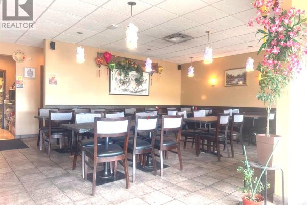 Seating area of the restaurant with booths along the wall and tables with chairs. - 10, 11225 30 Street Sw, Calgary