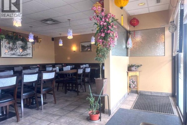 Corner of the restaurant dining room with tables, chairs, and an entrance area. - 10, 11225 30 Street Sw, Calgary