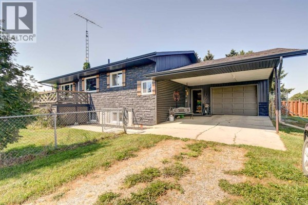 Side exterior view of a dark grey split-level house with a carport, garage, and driveway. - 10, 1342 Township Road 361, Rural Red Deer County