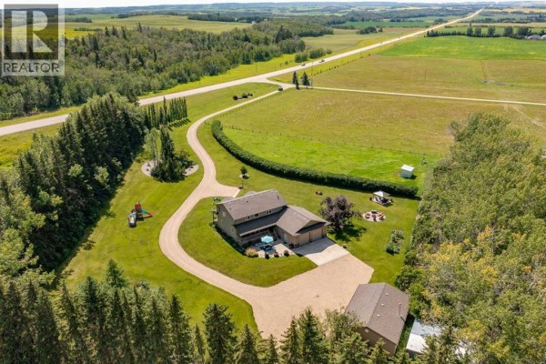 Aerial view of the property showing the house, a detached garage, a long driveway, and surrounding fields. - 10, 25028 Highway 595, Rural Red Deer County