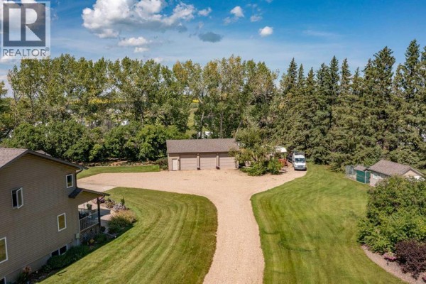 Aerial view of a detached three-car garage, a travel trailer, and outbuildings on a gravel driveway. - 10, 25028 Highway 595, Rural Red Deer County