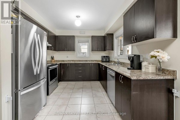 Kitchen with stainless steel appliances, dark cabinets, granite counters, tile floor - 10 - 200 Veterans Drive, Brampton
