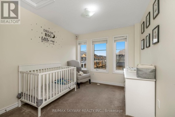 Nursery room with white crib, dresser, and three windows - 10 - 200 Veterans Drive, Brampton