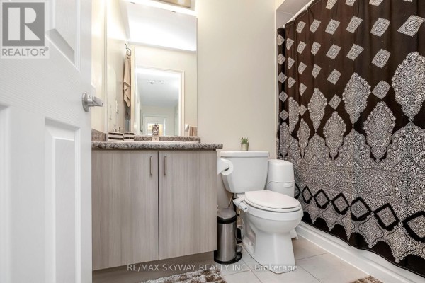 Modern bathroom with vanity, mirror, toilet, and shower curtain - 10 - 200 Veterans Drive, Brampton