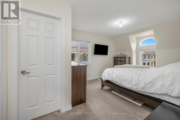 Bedroom with bed, dresser, mounted TV, and arched window - 10 - 200 Veterans Drive, Brampton