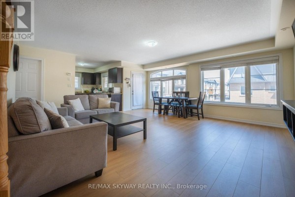 Modern open concept living and dining area with hardwood floors and dark kitchen cabinets - 10 - 200 Veterans Drive, Brampton