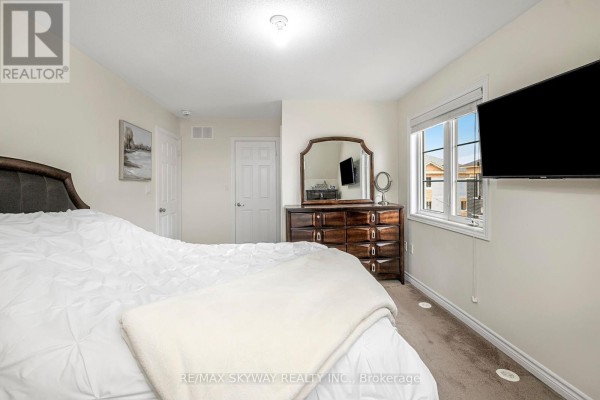 Modern bedroom with wall-mounted TV, window, and carpet - 10 - 200 Veterans Drive, Brampton