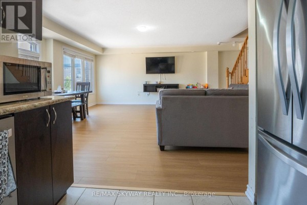 Open concept living room, dining area, kitchen with laminate floors, stainless refrigerator - 10 - 200 Veterans Drive, Brampton