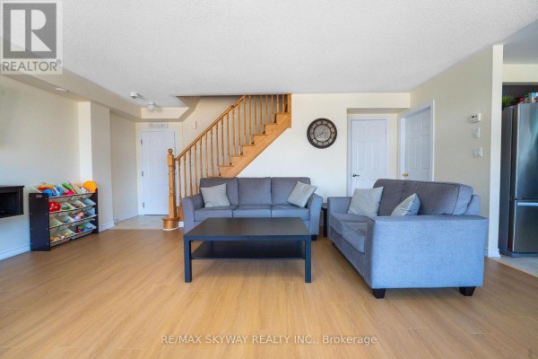Living room with wood-look flooring, wooden staircase, and sofas - 10 - 200 Veterans Drive, Brampton