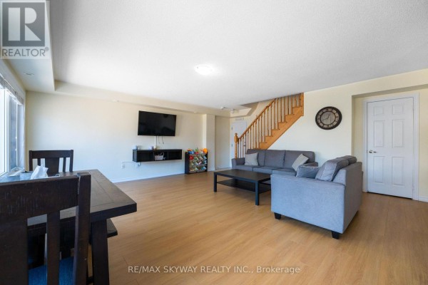 Living room with wood floors, wall-mounted TV, and staircase - 10 - 200 Veterans Drive Brampton